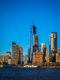 Sea by modern buildings against clear blue sky