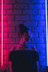 Young woman standing against brick wall