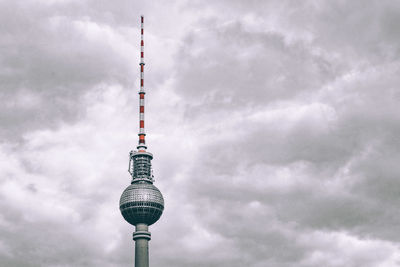 Low angle view of communications tower against cloudy sky