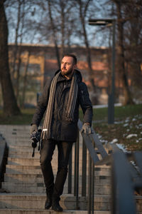 Young man in warm clothing moving down on steps at park