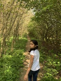 Side view of teenage girl standing in forest