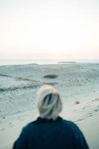 Rear view of man on beach against clear sky