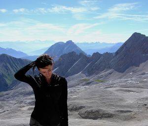 Young woman standing on mountain against sky