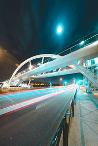 Light trails on bridge in city against sky at night
