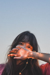 Portrait of young woman against clear sky