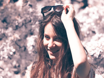 Portrait of smiling young woman against trees