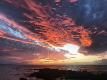 Scenic view of sea against dramatic sky during sunset