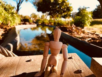 Figurine on table against trees during sunny day