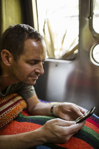 Mature man using phone in camper trailer