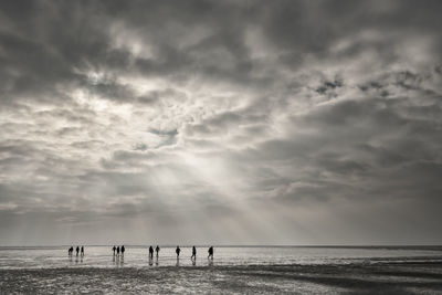 Silhouette people on beach against sky 