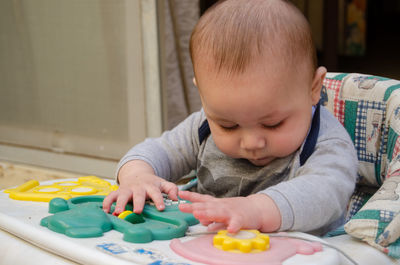 Cute boy looking down while playing with toys on table