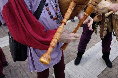 Midsection of male street artist playing bagpipe on footpath