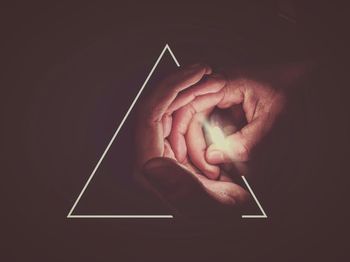 Close-up of hand holding cigarette over black background