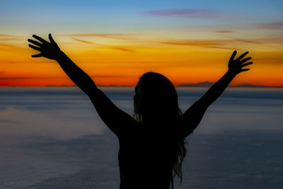 Silhouette woman hand in sea at sunset