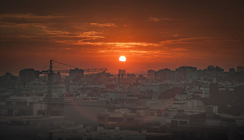 Buildings in city against romantic sky at sunset