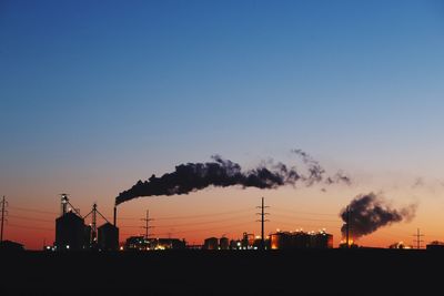 Smoke emitting from factory against sky during sunset