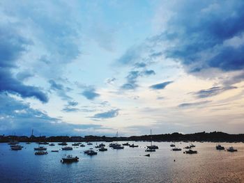 Sailboats moored in sea against sky during sunset