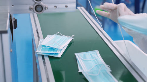 Cropped hand of person manufacturing flu mask at factory