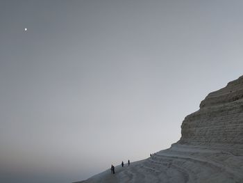 People on rock formation against sky