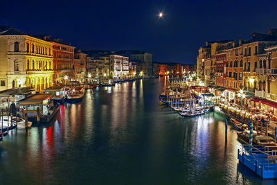 Boats moored on illuminated city at night