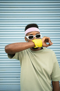 Young man covering mouth with hand in front of blue shutter