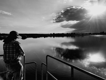 Man fishing at lake against sky