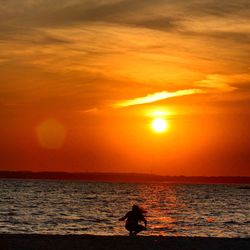 Silhouette man on beach against sky during sunset