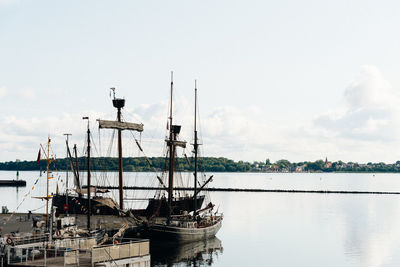 Sailboats moored in sea against sky