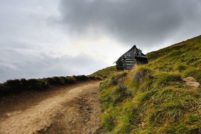 Dirt road amidst buildings against sky