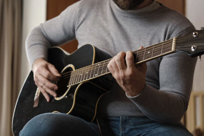 Midsection of man playing guitar