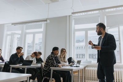 Professor teaching students sitting in classroom