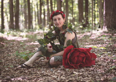 Portrait of smiling woman sitting on land in forest