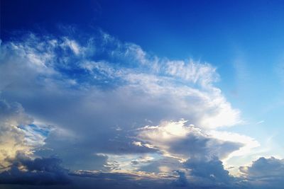 Low angle view of sunlight streaming through clouds