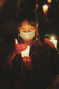 Close-up of woman holding lit candle