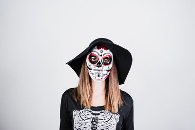 Portrait of young woman wearing mask against white background