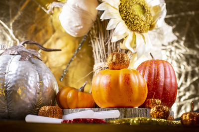 Pumpkins, red, yellow, and orange glitter leaves, and dried sunflowers against a golden background