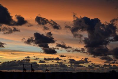 Low angle view of silhouette landscape against dramatic sky during sunset