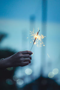 Close-up of hand holding sparkler against blurred background