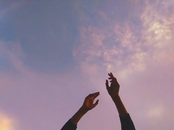 Two hands up in the pink sky