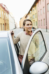 Businesswoman looking away while entering car on street