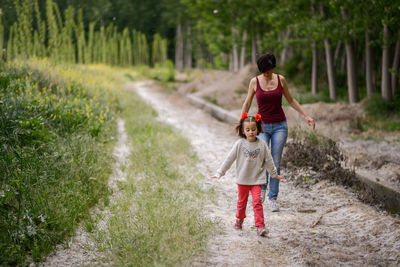 Mother and daughter walking on field at public park