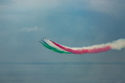 Red airplane flying over sea against sky