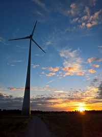 Windmill on field against sky during sunset