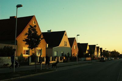 Street amidst buildings against clear sky at sunset