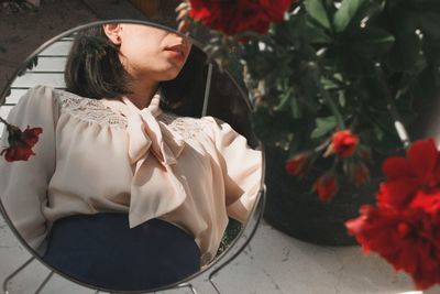 Young woman looking down while sitting on plant