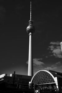 Low angle view of communications tower in city against sky