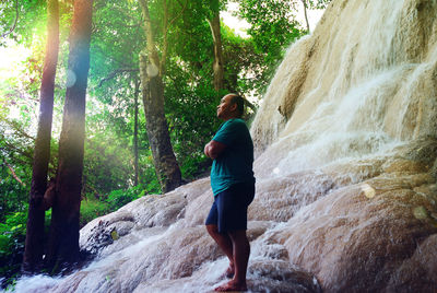 Full length of man standing on rock in forest