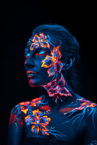 Portrait of woman with multi colored light painting against black background