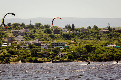 Kitesurfers against sky on sunny day