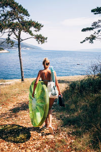 Rear view of woman with pool raft walking at beach